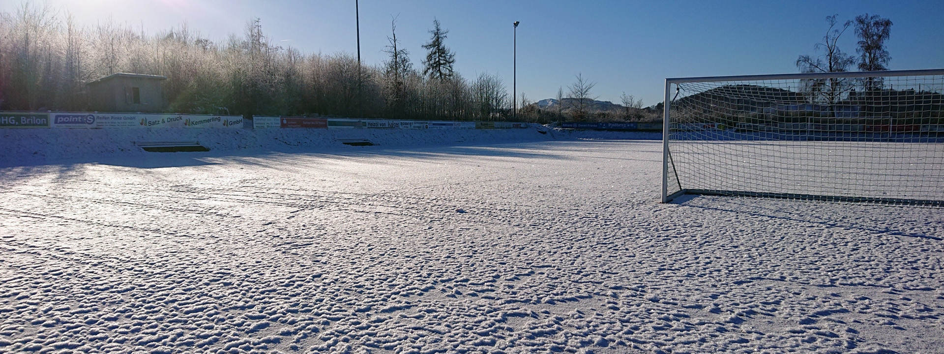 Sportrasenfeld im Winter mit Schneedecke